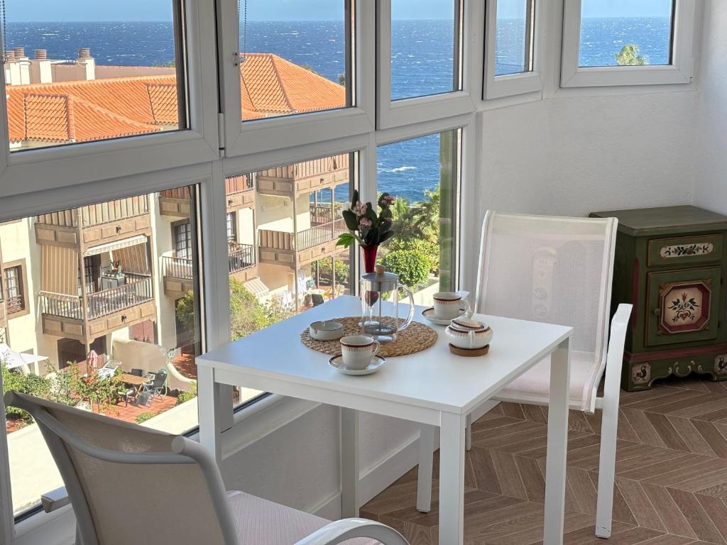 a white table and chairs in a room with windows at Cozy Studio with Seaview in Costa Del Silencio