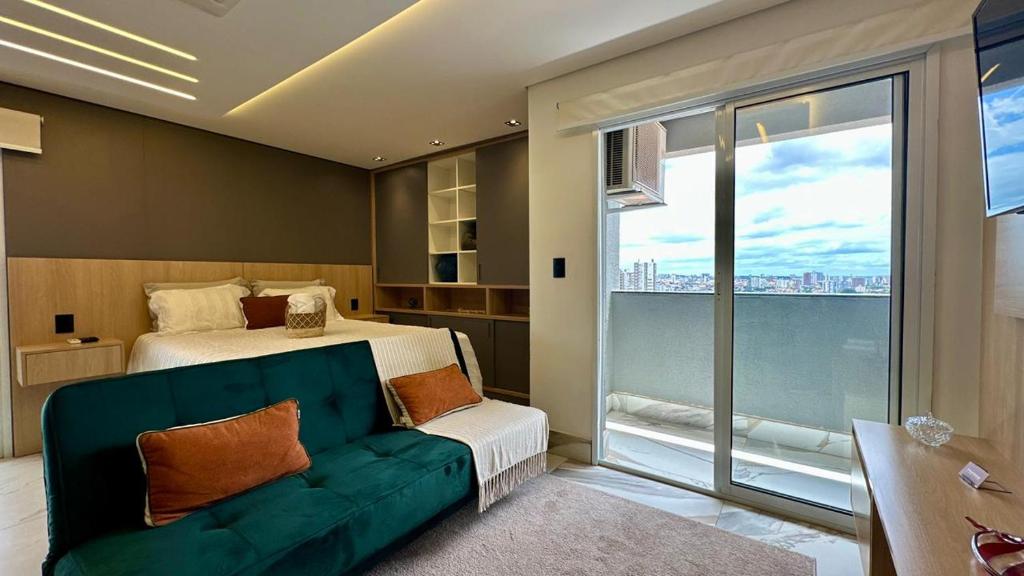 a bedroom with a bed and a couch and a window at Studio Red 10 - Sorocaba in Sorocaba