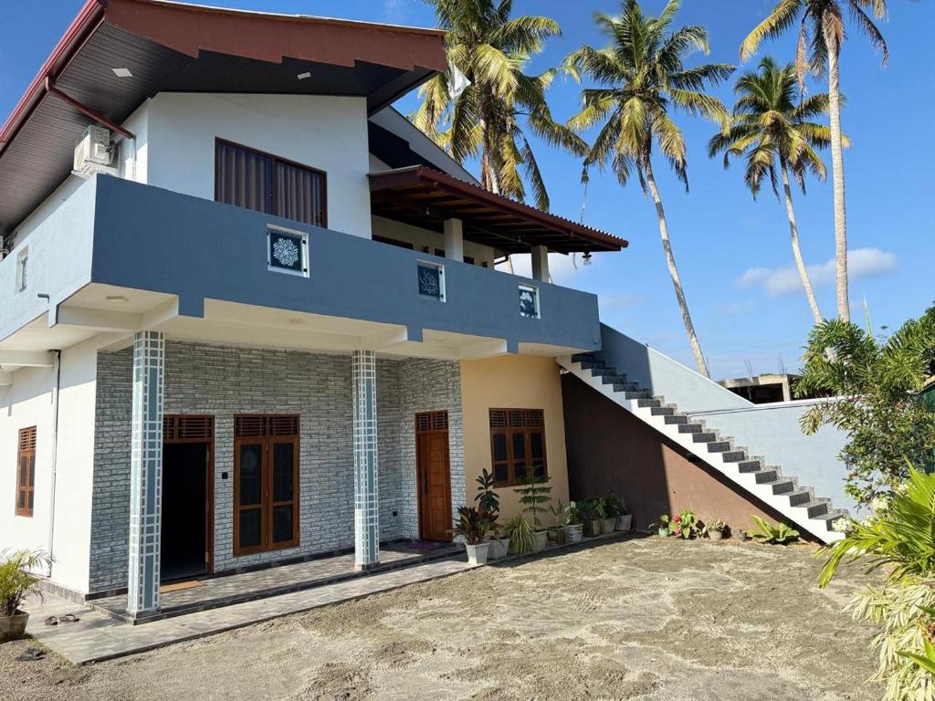 a house with a blue roof and palm trees at Apollo Villa Weligama in Weligama