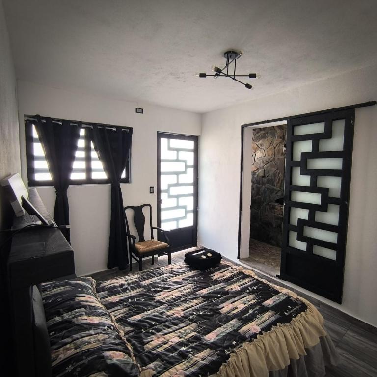a bedroom with a bed and a chair and windows at Hospedaje Don Juve in Atlixco