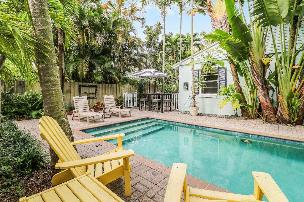 a swimming pool with two chairs and a house at Cottage 3 on Penn - Pool in West Palm Beach