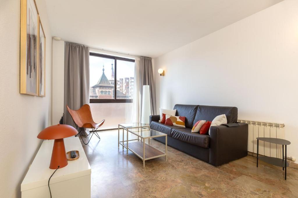 a living room with a black couch and a window at Picasso Suites in Barcelona