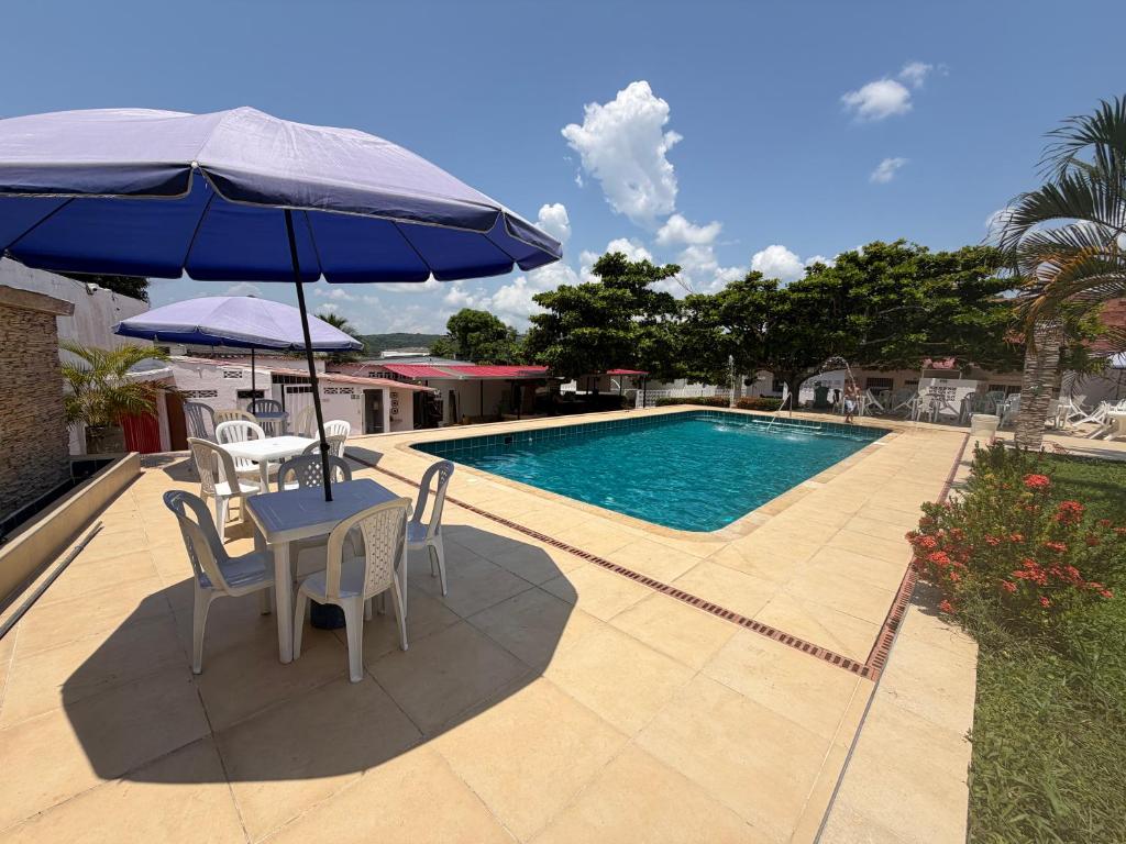 a table and chairs with an umbrella next to a pool at Brisas de melgar in Melgar
