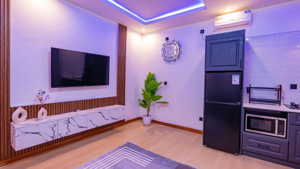 a living room with a tv and a black refrigerator at K&K Luxurious Landing in Limbe