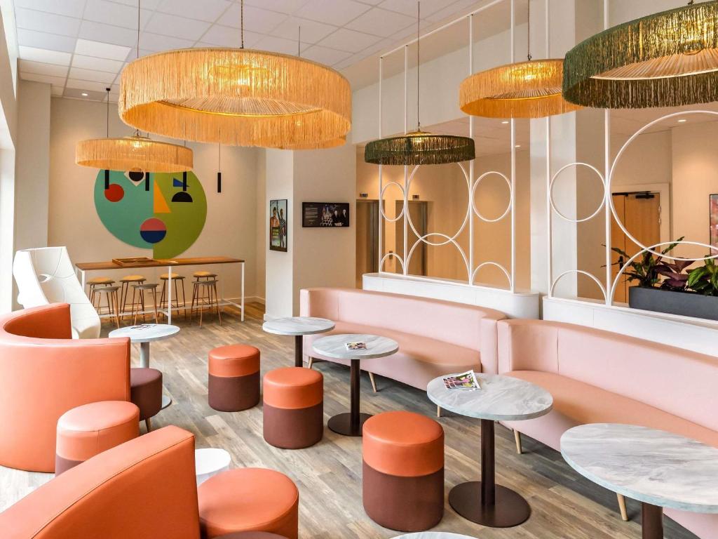 a restaurant with pink and orange furniture and tables at ibis Styles Metz Centre in Metz