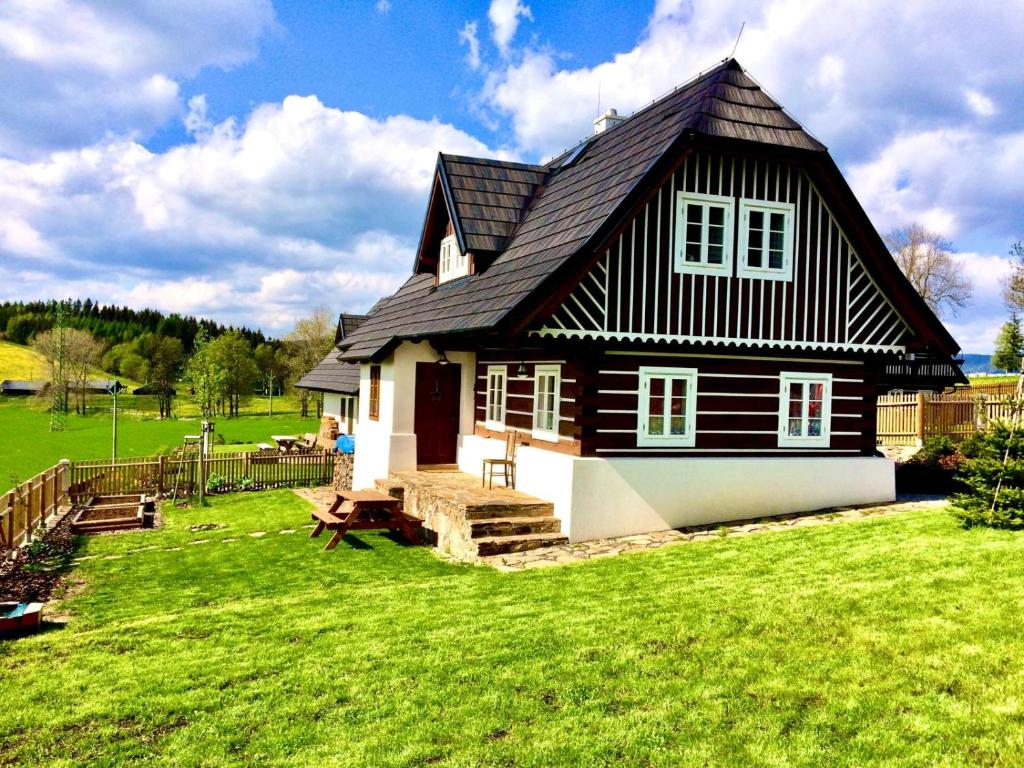 a black and white house on a green field at Chalupa U Pastýře in Vysoké nad Jizerou