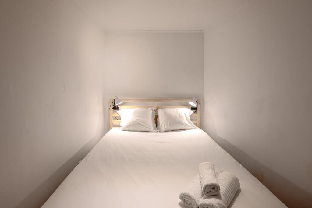 a bed with white sheets and towels on it at Alfama Tiny by Homing in Lisbon