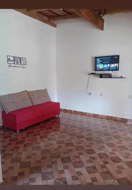 a red couch in a room with a flat screen tv at Recanto Soares in Mucuri