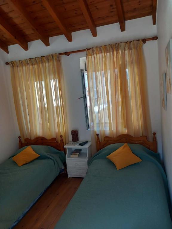 a bedroom with two twin beds and a window at Giannis' House in Polichnítos