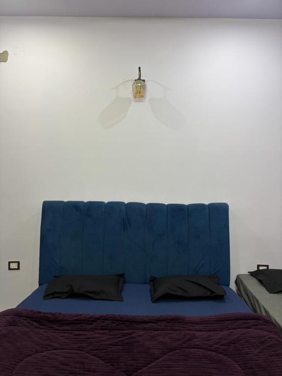 a bed with a blue headboard against a white wall at Manavi Home Stay in Mathura