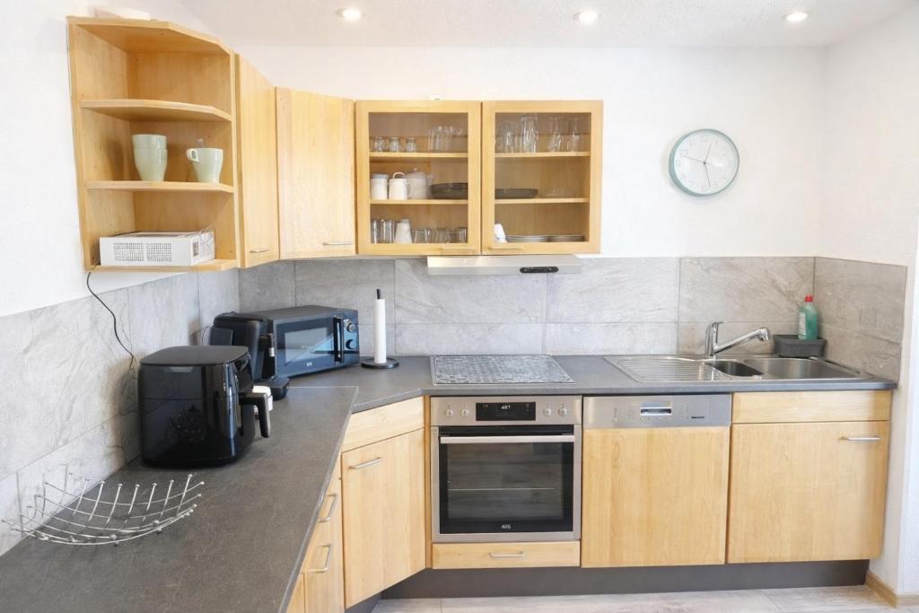 a kitchen with wooden cabinets and a sink and a microwave at Ferienwohnung AyNa 2, direkt an der Schweizer Grenze in Bad Säckingen