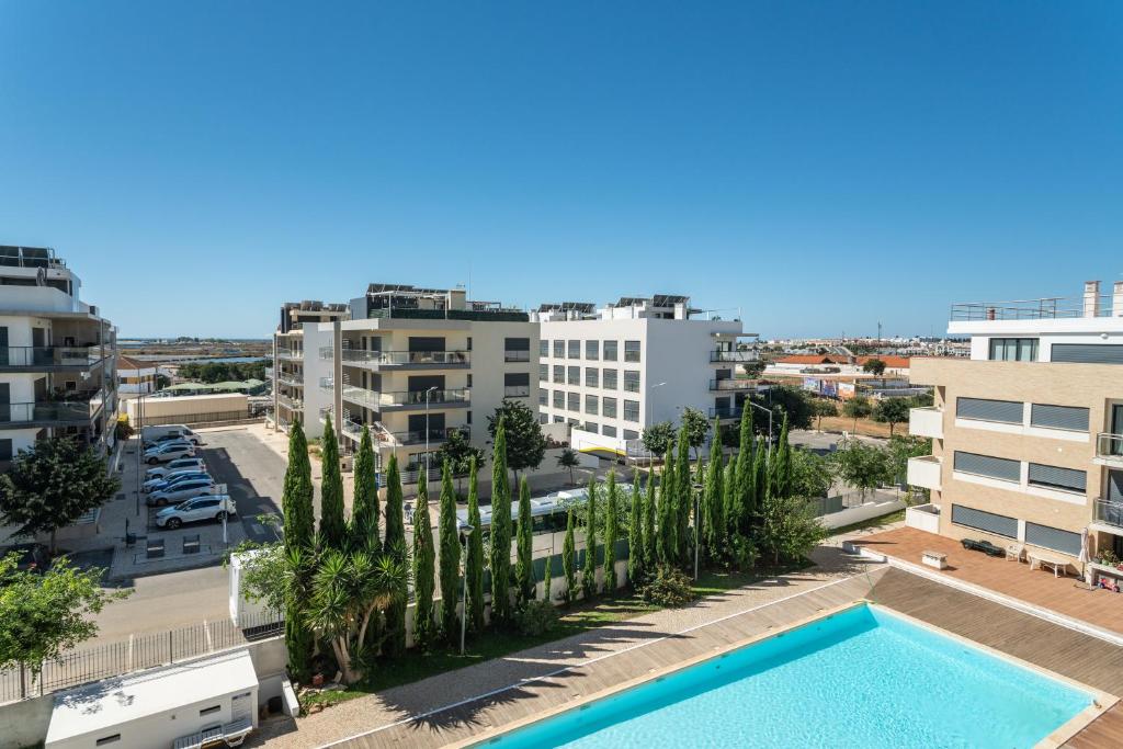 an apartment with a swimming pool and palm trees at Santa Maria Apartamentos in Tavira