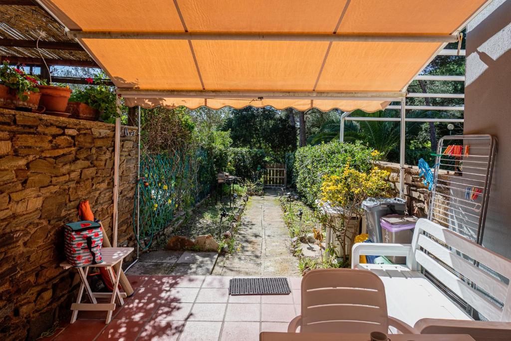 an outdoor patio with an orange umbrella and a garden at Cala Lupo Relax Veranda e BBQ nel verde in Stintino