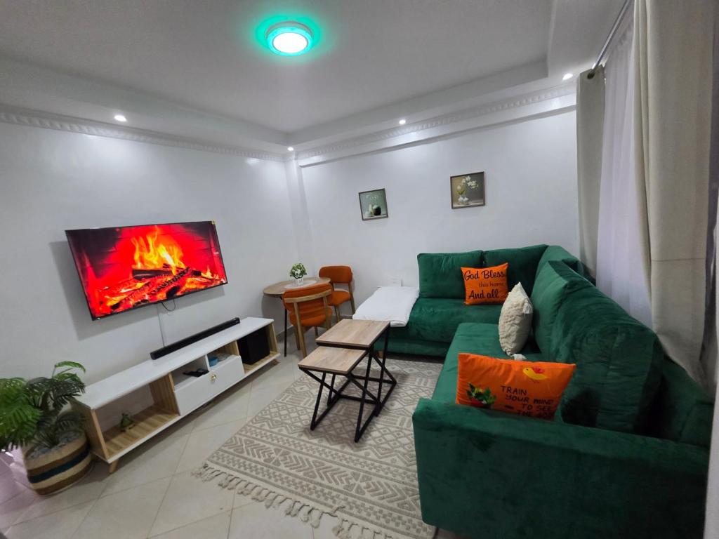 a living room with a green couch and a flat screen tv at Waridi Homes One-bedroom Naivegas Apartment in Naivasha