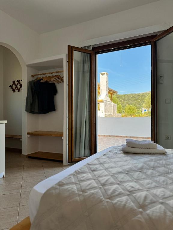 a bedroom with a bed and a large glass door at Limnes Seaside Studio in Ligaridia