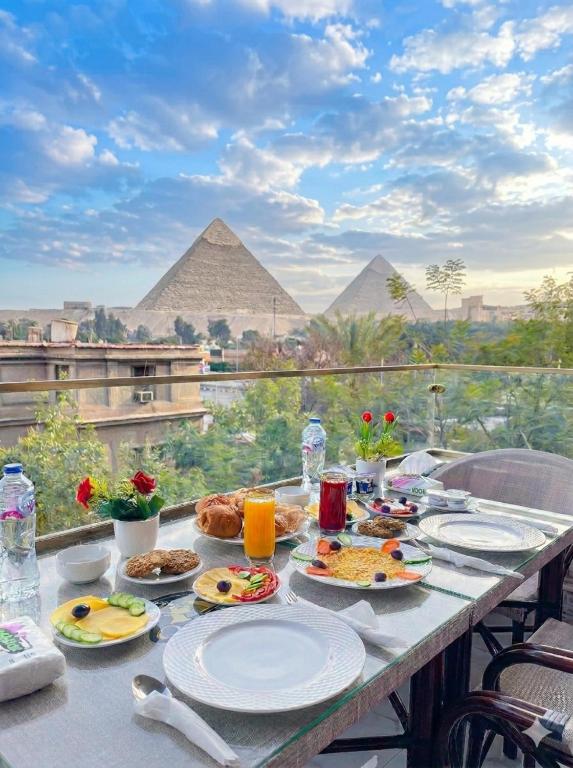 a table with food on it with the pyramids in the background at Queen Inn Pyramids View in Cairo