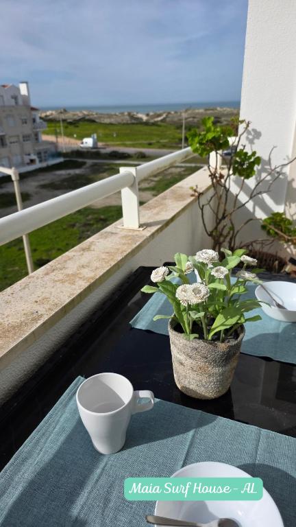 a table with a cup and a plant on a balcony at Maia Surf House - Baleal in Ferrel