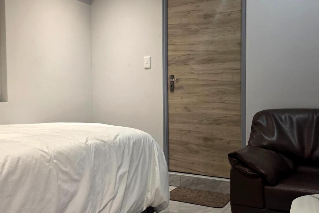 a bedroom with a bed and a chair and a door at Ijumba Signature Hotel in Bellville