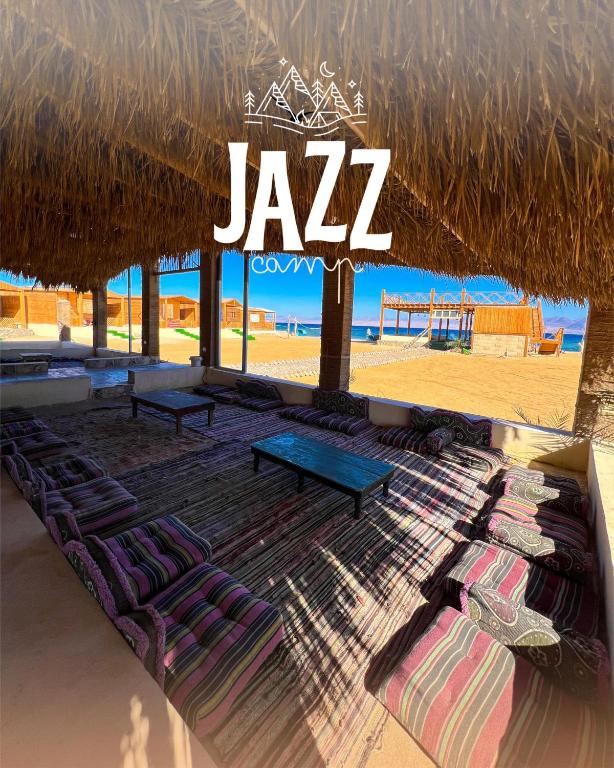 a group of lounge chairs under a straw umbrella on a beach at Jazz Nuwibaa Camp in Wāsiţ
