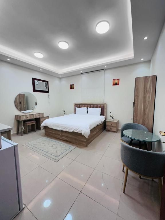 a bedroom with a bed and a desk and a table at Quba Suites نزل قباء in Medina