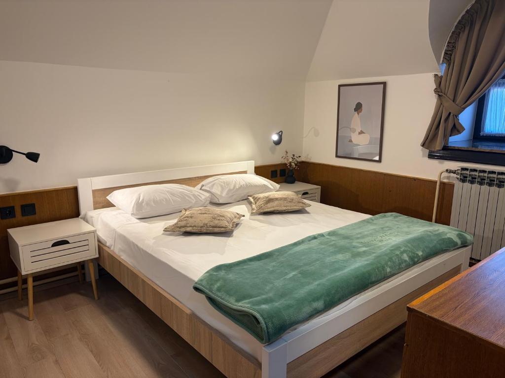 a bedroom with a bed with a green blanket on it at Guest house Royal in Čakovec