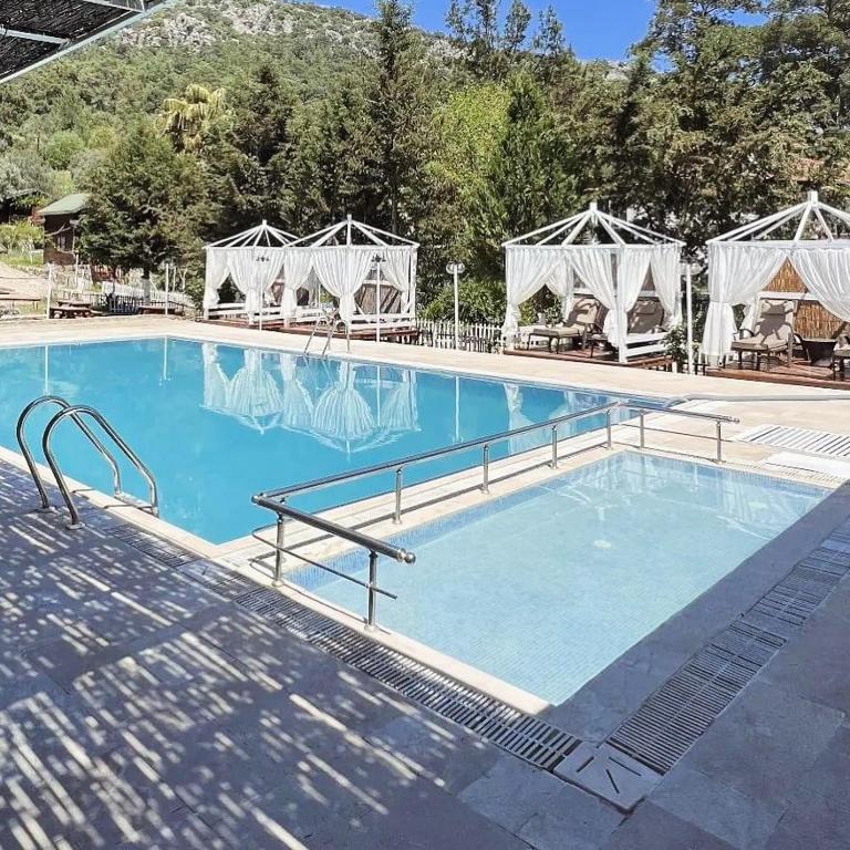 a large blue swimming pool with a gazebo at arzum bungalovs in Kumluca