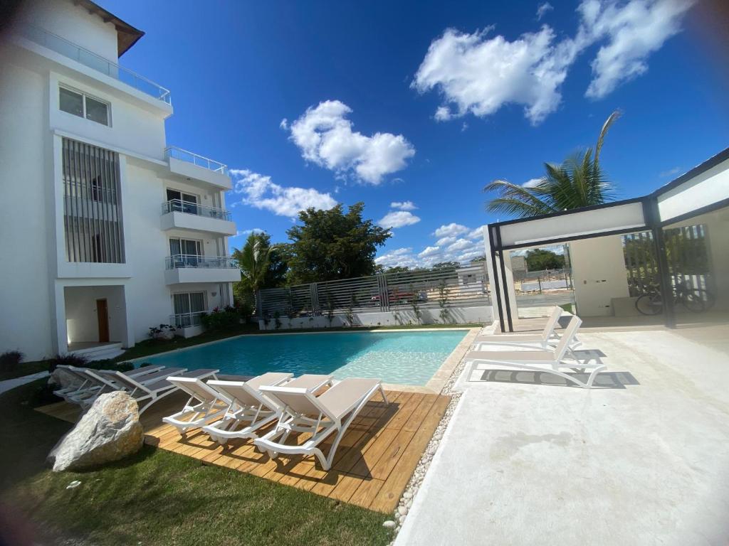 a swimming pool with lounge chairs next to a building at Apartamento Vacacional Coral Azul - SBH in Bayahibe
