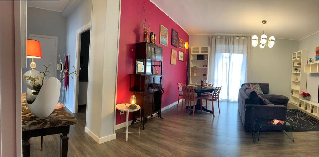a living room with a pink accent wall and a table at Vespro 1 Apartment - near the Greek theater in Syracuse
