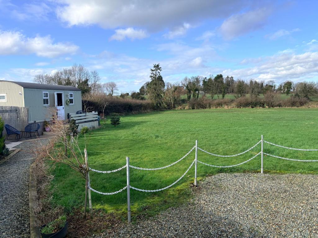 a fence in front of a large grass field at Whitethorn Shepherds Hut in Bellaghy