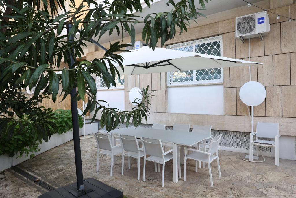 a table with chairs and a white umbrella in a courtyard at Sweet Home Fleming in Rome