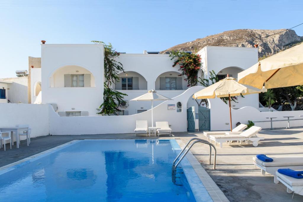 a pool with chairs and umbrellas in front of a building at Atlas Boutique Hotel in Kamari