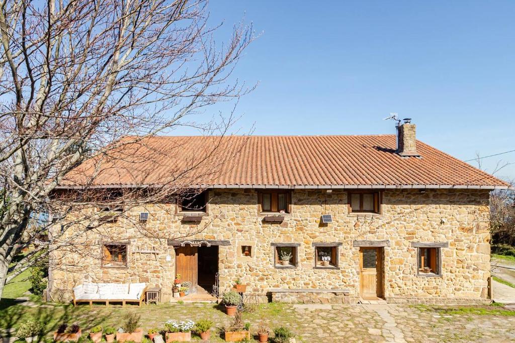 an old stone house with a red roof at Golindo Goikoa in Getaria