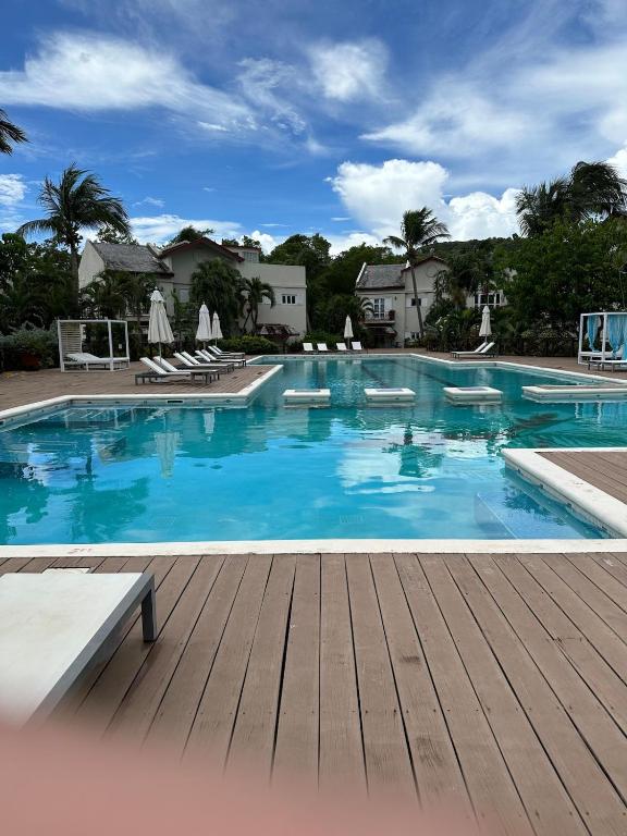 a large swimming pool with a wooden deck at Charming poolside condo in Cap Cove in Cap Estate