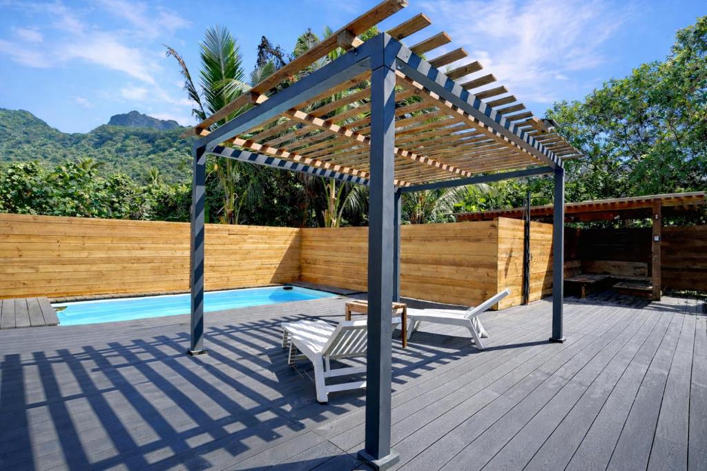a wooden deck with a pergola next to a pool at POOL AC King Bed Cozy Rooms - Villa Vaiaire in Vaïare