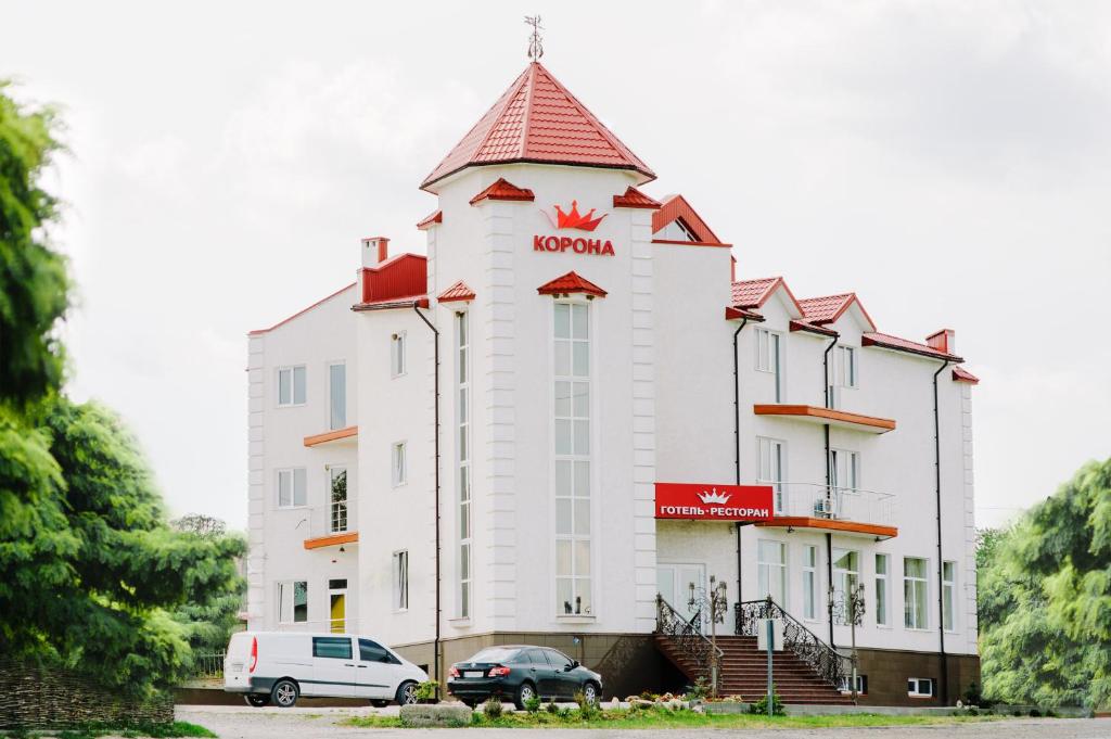 un gran edificio blanco con techo rojo en Hotel Korona, en Kolybayevka