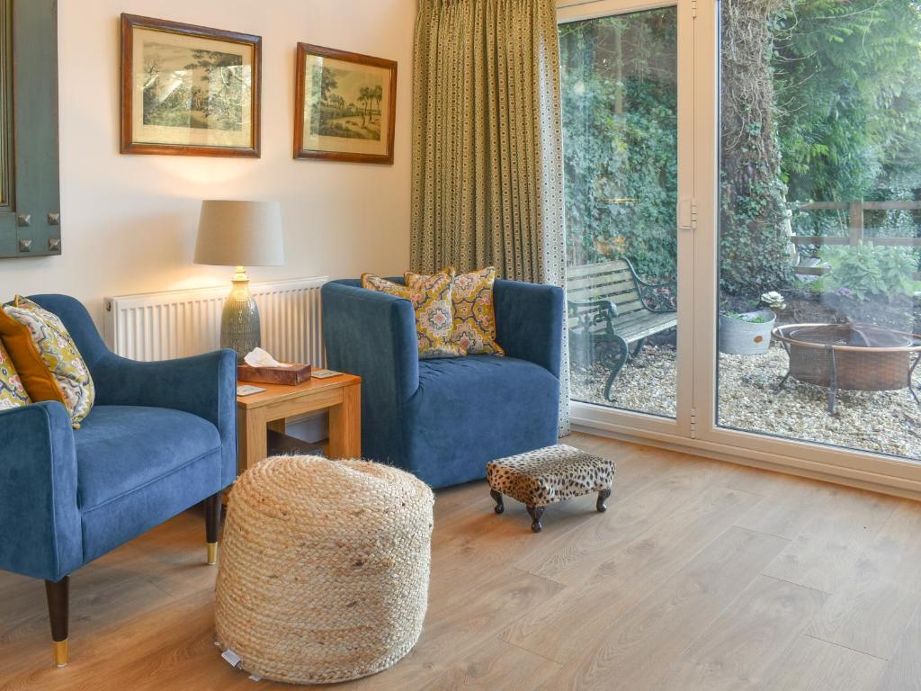 a living room with two blue chairs and a window at South Downs Lodge in Soberton