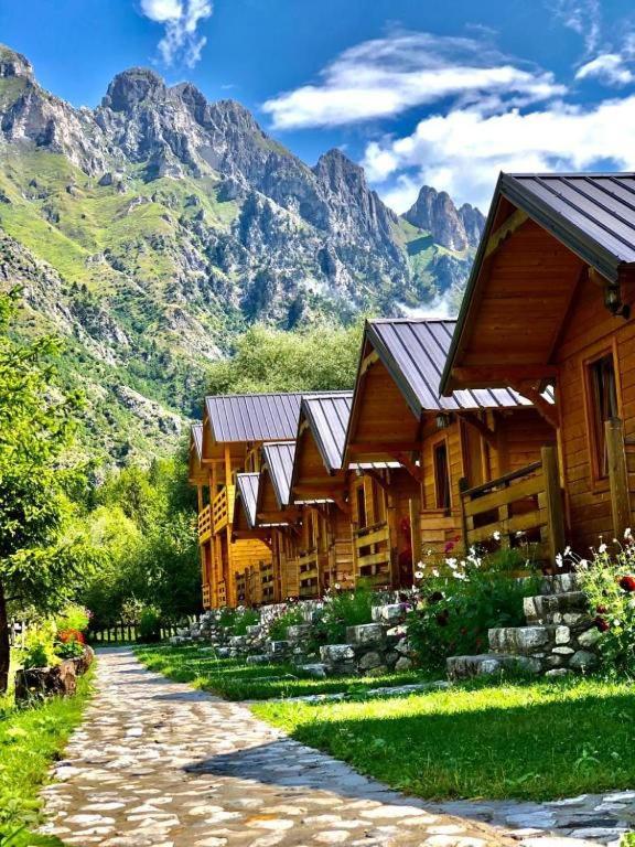 una fila di case di legno con le montagne sullo sfondo di Villas Jezerca a Valbona