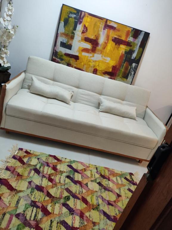 a white couch in a living room with a painting at Loft 101 in Rio de Janeiro