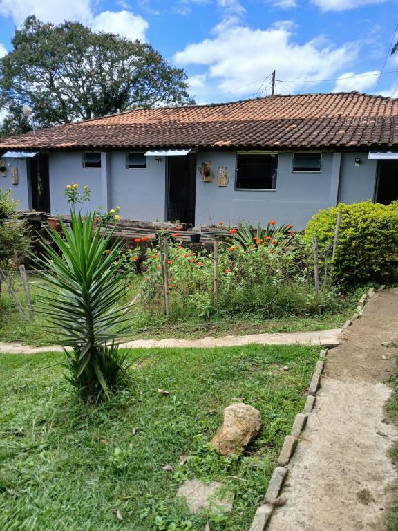 a house with a garden and a palm tree at Pousada Recanto Alegre in Campestre