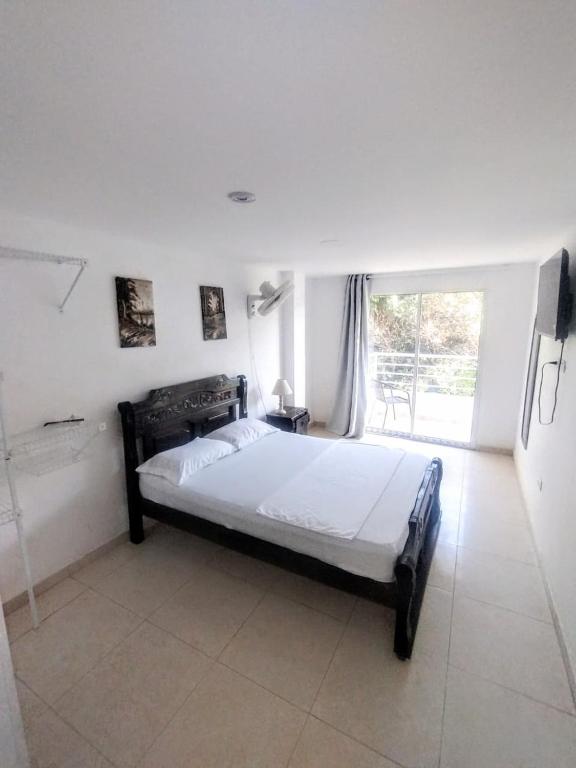 a bedroom with a bed and a large window at Hotel Taganga Plaza Santa Marta in Taganga