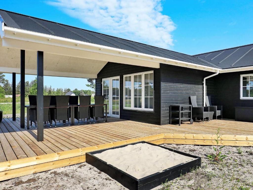 a deck with chairs and tables on a house at 8 person holiday home in Læsø in Læsø