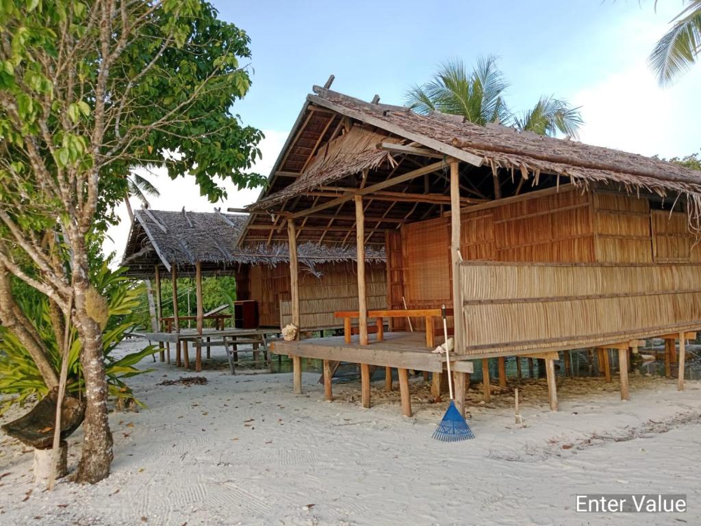 a hut on the beach with a bench in front at War Nyampun Homestay in Waisai