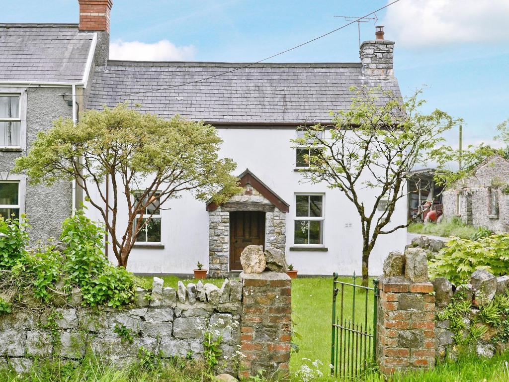 a white cottage with a stone fence and trees at Murton Farm Cottage in Horton