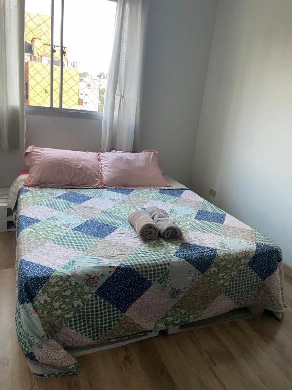 a bed with a quilt and two towels on it at Quarto Privado em Apto Bigorrilho in Curitiba