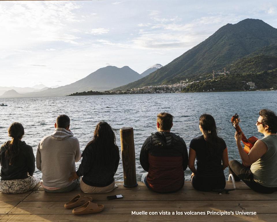 a group of people sitting on a dock by the water at Principitos Universe in San Juan La Laguna