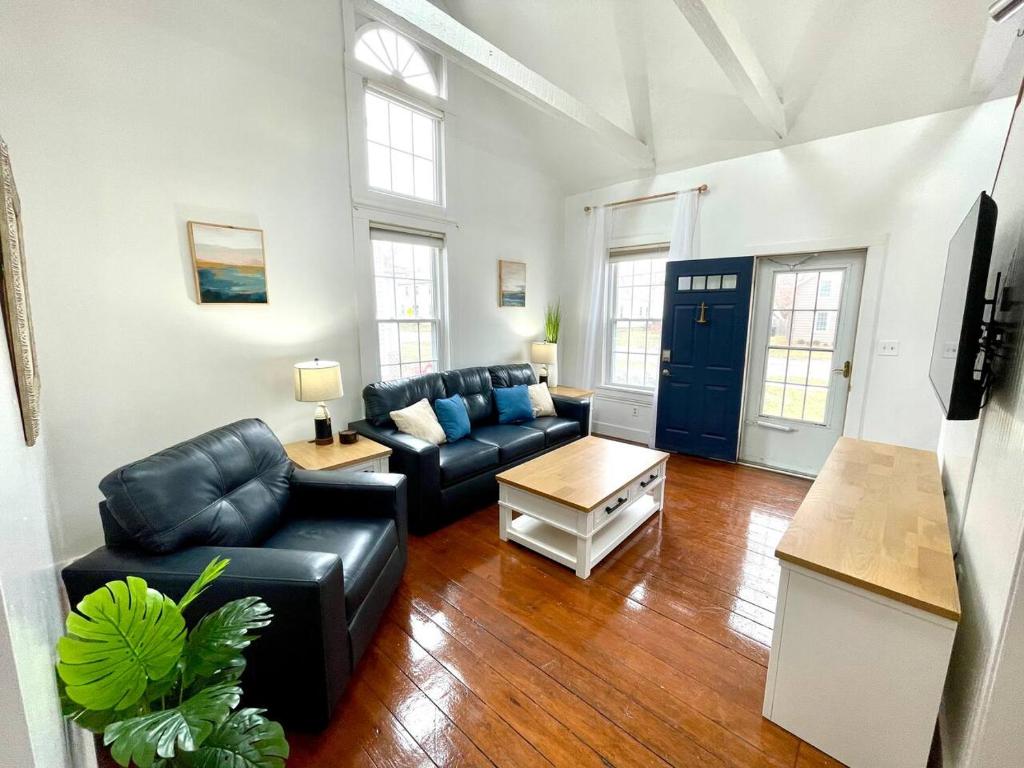 a living room with black leather couches and a table at Coastal Cape Cod w/ King Bed, Game Room, & Bikes! in Vermilion