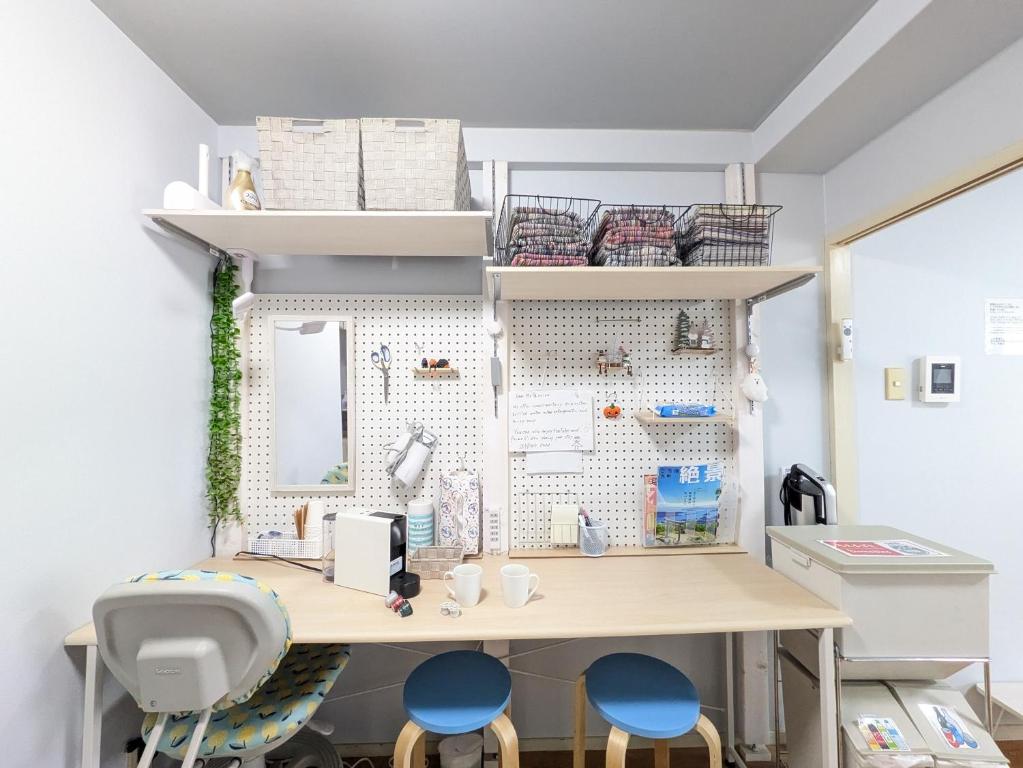 a room with a desk and two blue chairs at エルビスコート井尻101号 in Morooka