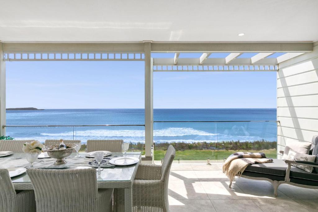 a dining room with a table and a view of the ocean at Waves at Warilla in Barrack Point