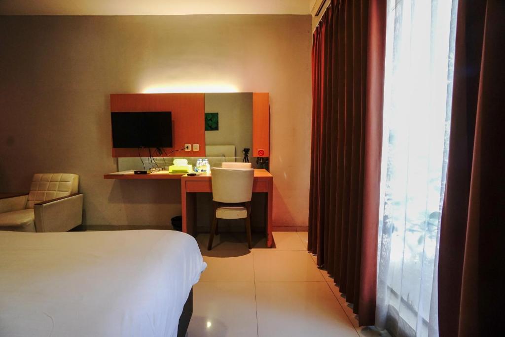 a hotel room with a bed and a desk with a computer at Buring Residence By TOS Malang in Samaan