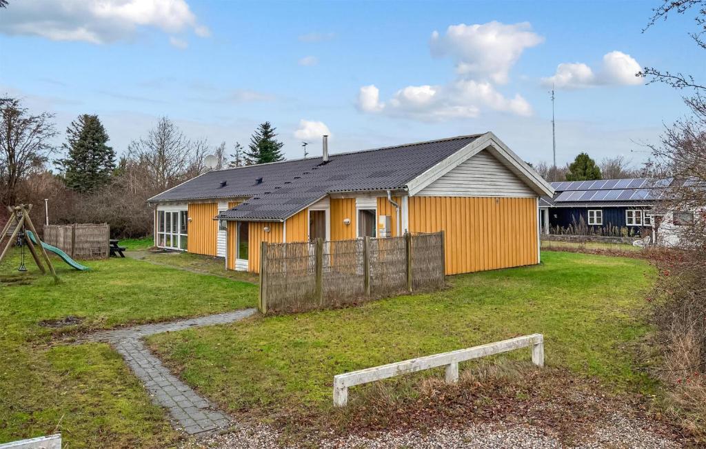 a yellow house with a fence in a yard at Amazing Home In Ørsted With Sauna in Ørsted
